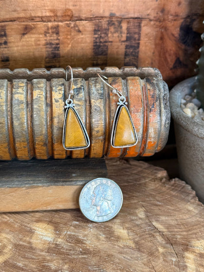 Silver fishhook earrings with teardrop yellow stone; coin shown for size scale
