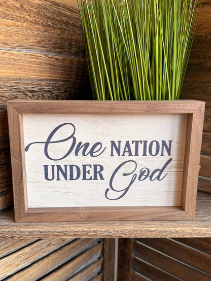 Framed artwork with "One Nation Under God" typography in blue, natural wood frame