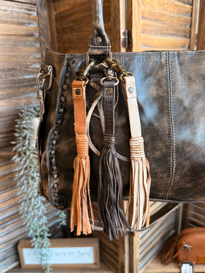 Leather tassel clips with dark and tan tassels on a leather tote