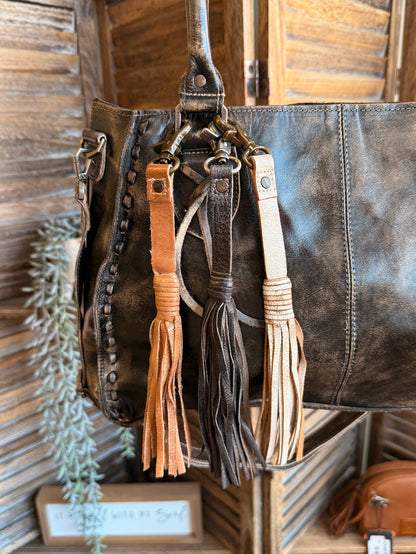 Leather tassel clips with dark and tan tassels on a leather tote