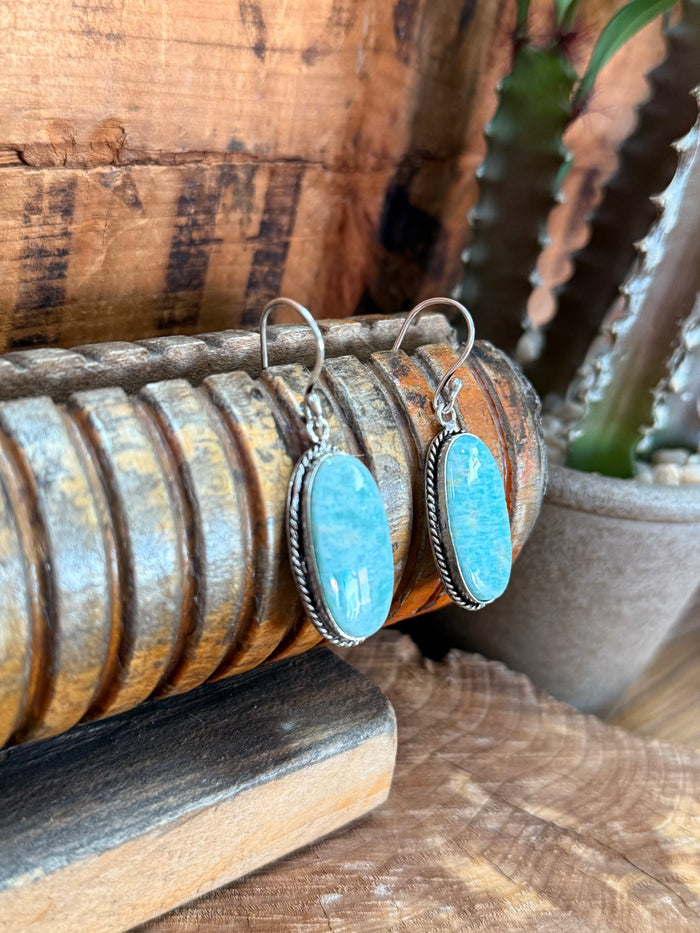 Silver fishhook earrings with oval blue cabochon stones and textured edge