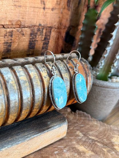Silver fishhook earrings with oval blue cabochon stones and textured edge