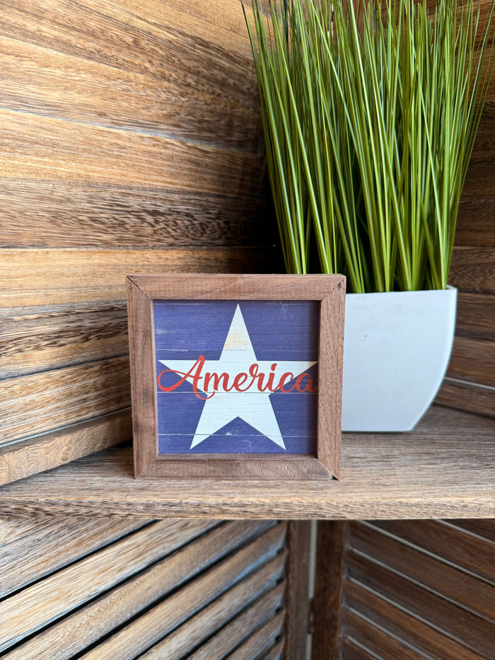 Framed blue star artwork with red "America" script in rustic wood 4x4 frame