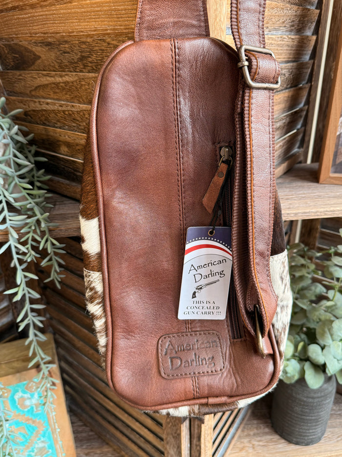 Brown leather sling bag back with cowhide side trim and American Darling label