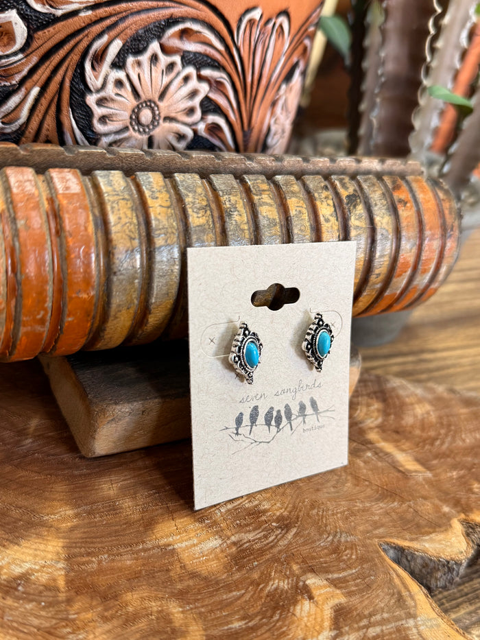 Turquoise oval stud earrings in silver diamond bezel with decorative scrolling frame