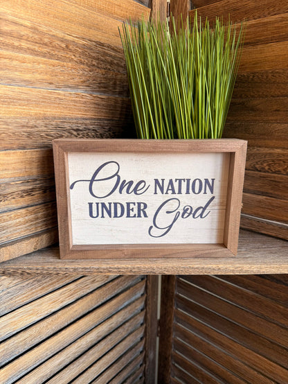 Framed wall artwork reading "One Nation Under God" with natural wood frame
