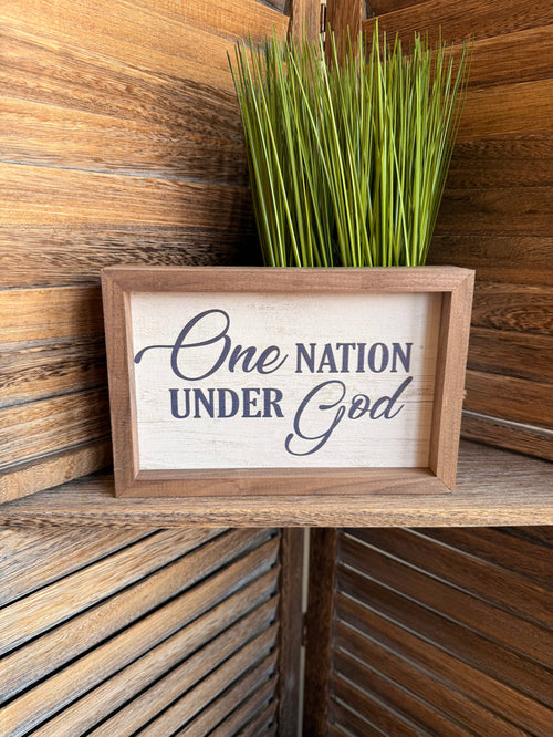 Framed wall artwork reading "One Nation Under God" with natural wood frame