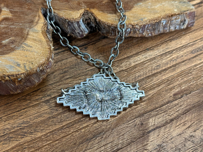 Silver cattle pendant necklace with ornate sunburst-edged cow medallion and chain