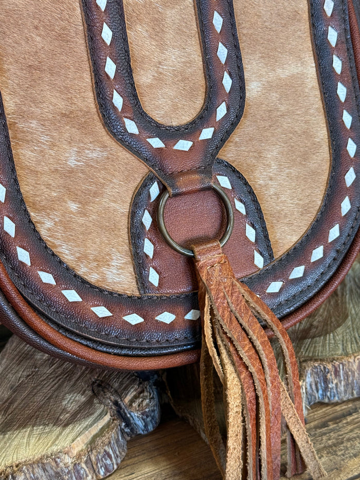 Cowhide flap crossbody bag detail: ring clasp, white diamond stitching, and fringe tassel