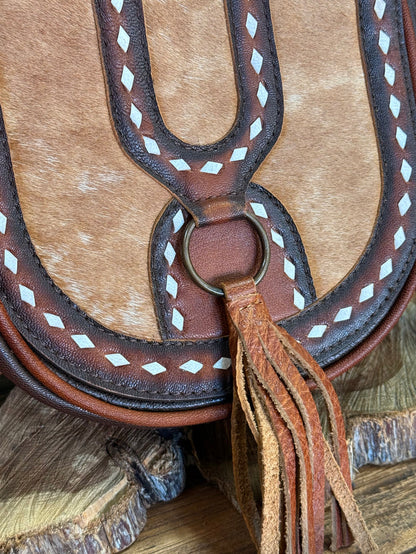 Cowhide flap crossbody bag detail: ring clasp, white diamond stitching, and fringe tassel