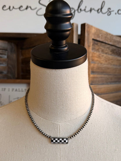 Checker bar necklace on a mannequin with silver chain and black-and-white checkered bar