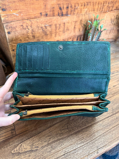 Green leather wallet open, showing bill slots and card compartments inside