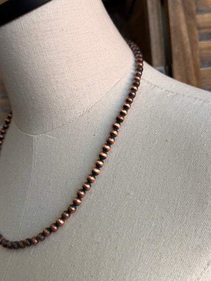 Copper bead necklace close-up on mannequin bust, evenly spaced beads