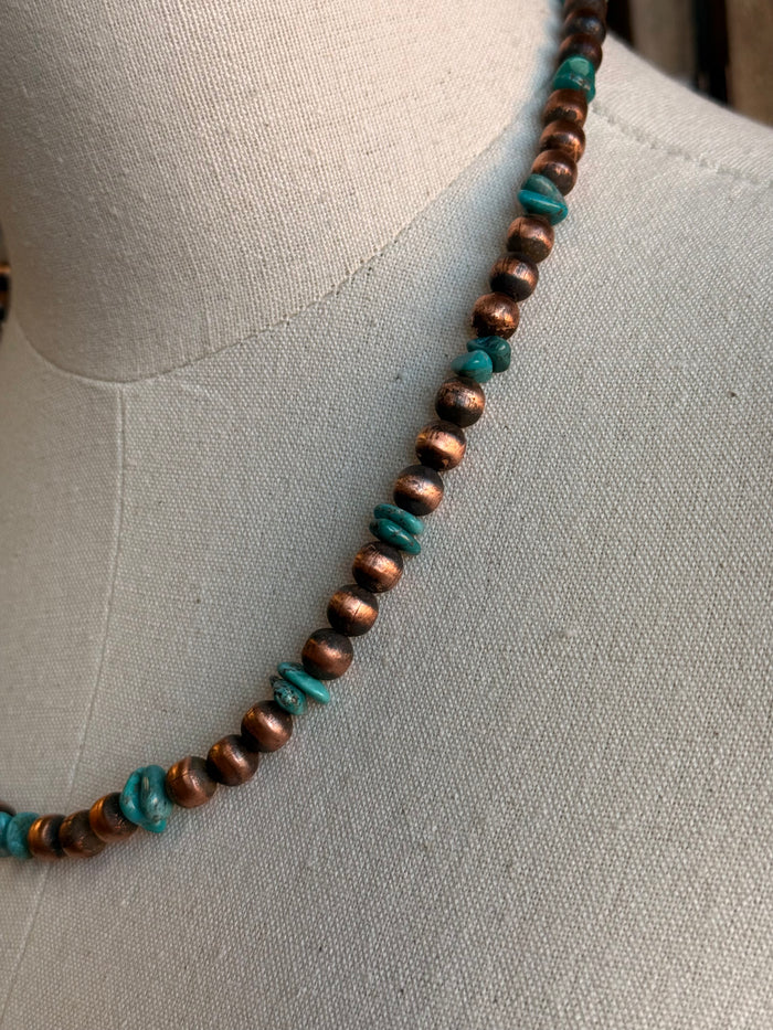 Copper and turquoise bead necklace detail along the neckline