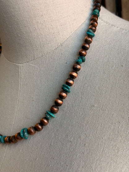 Copper and turquoise bead necklace detail along the neckline
