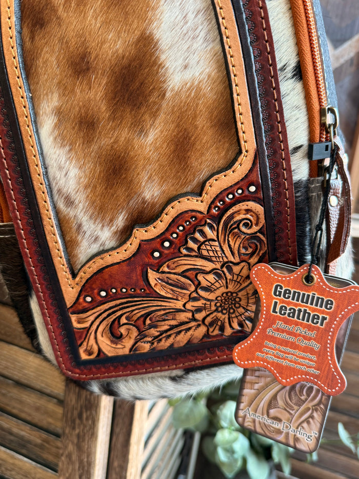 Cowhide sling bag front closeup with carved floral tooled leather and cowhide patch