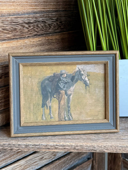Framed cowboy and horse wall art, close view of light canvas and gray frame