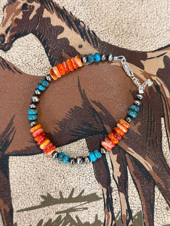 Beaded bracelet with orange bar beads, turquoise spacers, silver chain clasp