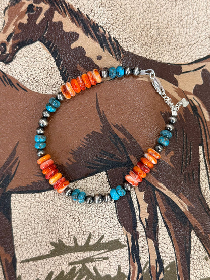 Beaded bracelet with orange bar beads, turquoise spacers, silver chain clasp