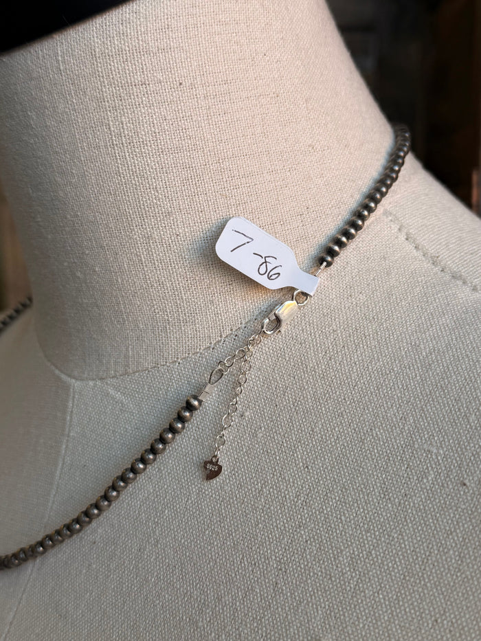 Sterling silver beaded necklace with small charm at clasp and tag detail
