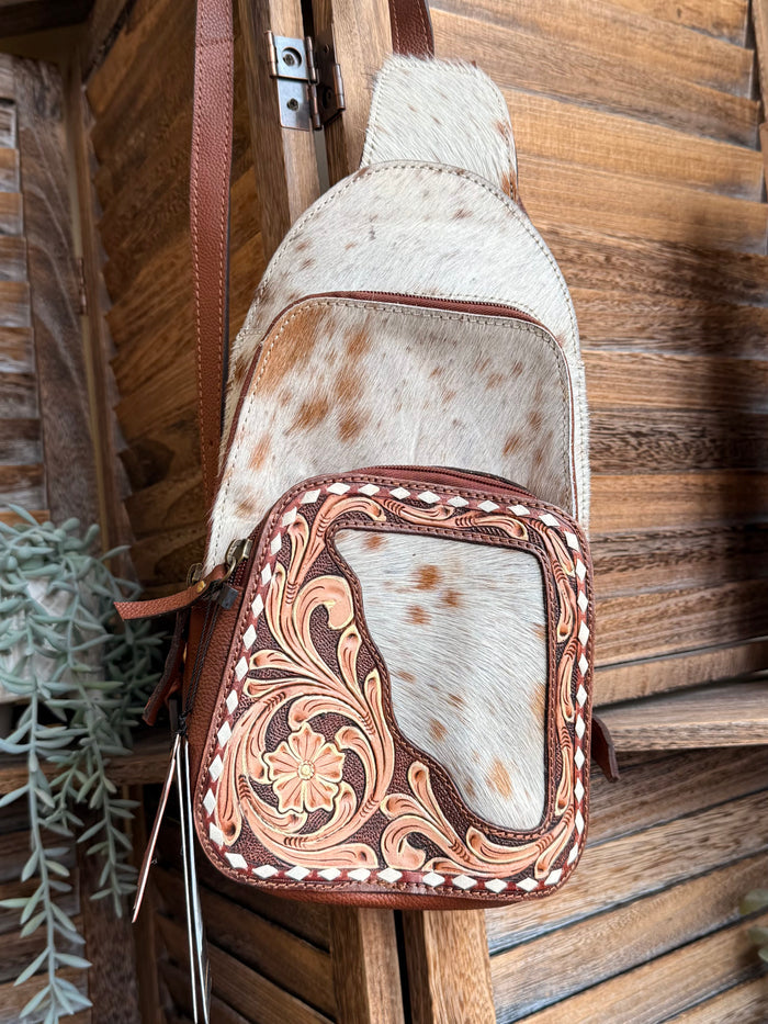 Hair-on cowhide sling backpack front pocket with brown floral border stitching