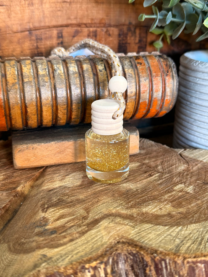 Mini reed diffuser with clear bottle containing golden oil and white stacked reed cap