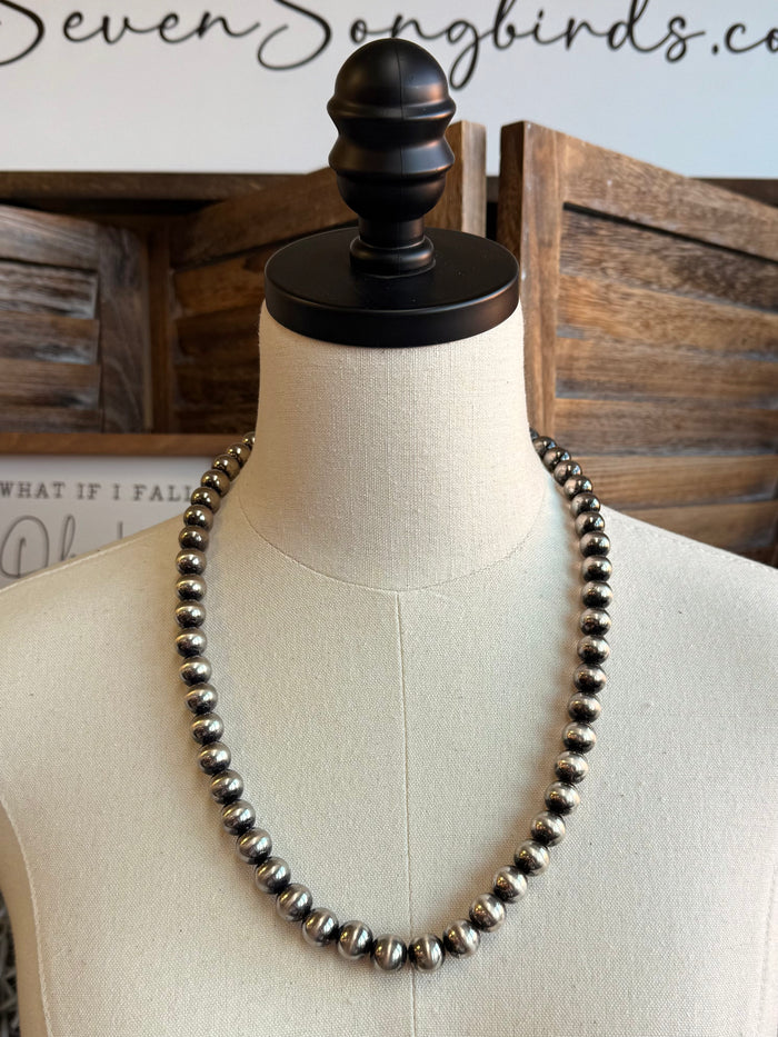 Silver pearl bead necklace laid in a long U shape on mannequin