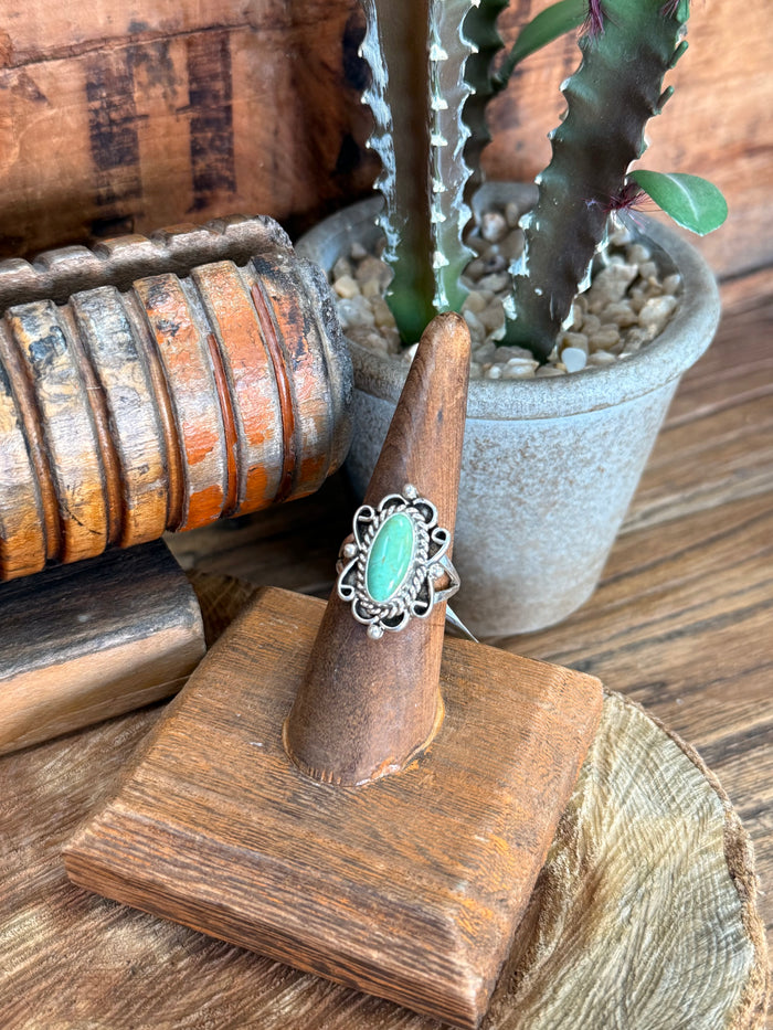 Turquoise oval sterling silver ring with ornate beaded details on finger display