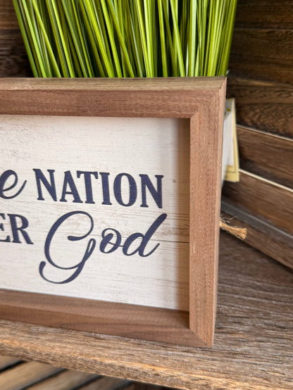 Framed artwork close-up with "Nation" and "God" lettering in blue, wood frame