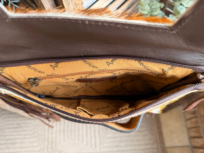 Zippered interior of brown leather clutch with tan patterned lining and text
