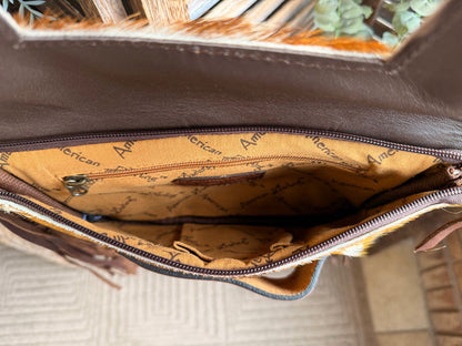Zippered interior of brown leather clutch with tan patterned lining and text