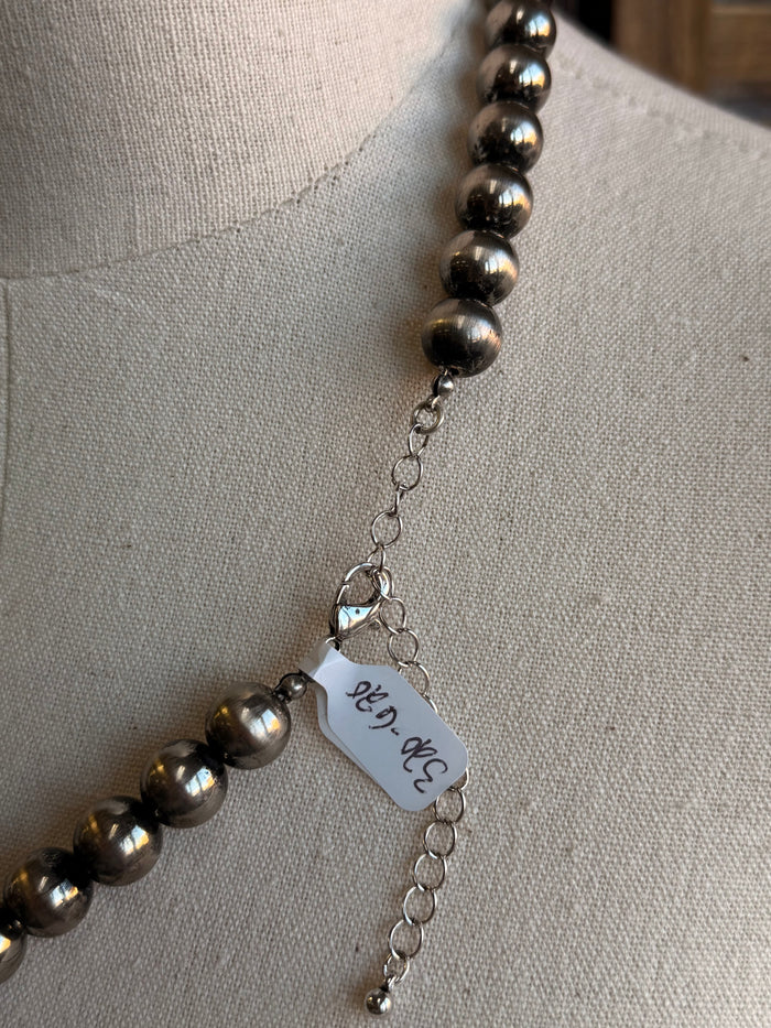 Close-up of silver pearl beads with small chain and charm tag