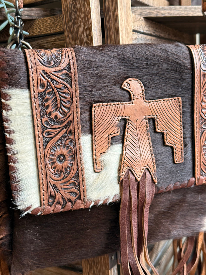 Cowhide crossbody purse with tooled leather cross applique, stitched border, and fringe ends