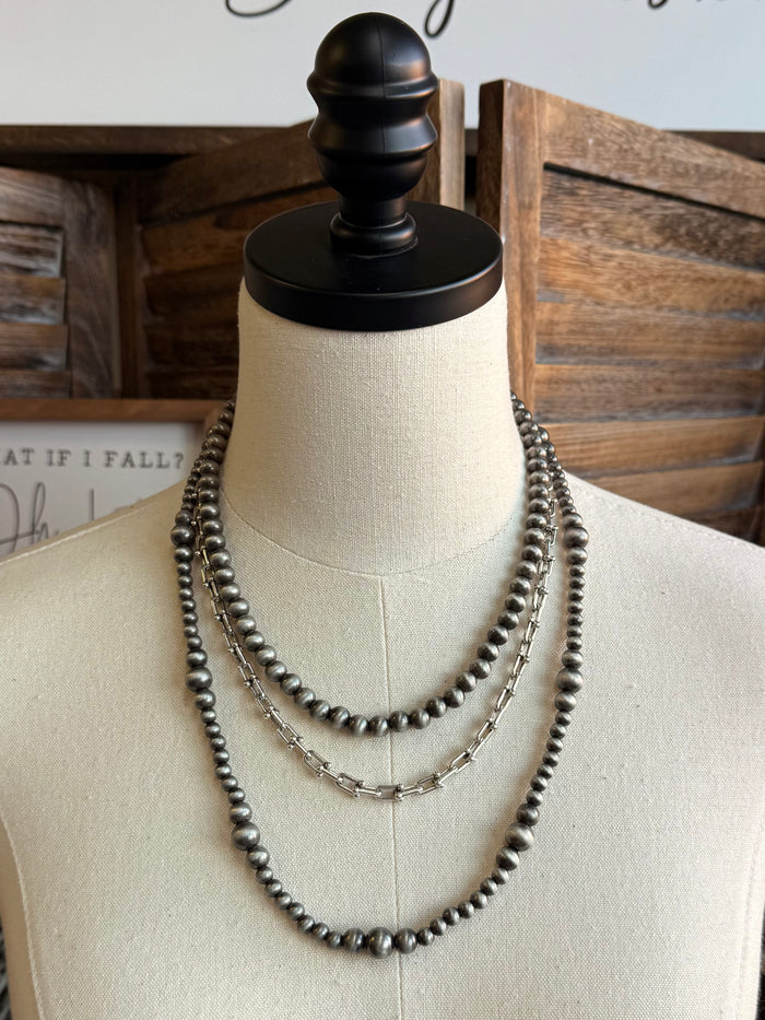 Triple pearl stack necklace with silver-tone beads, three layered chains on mannequin