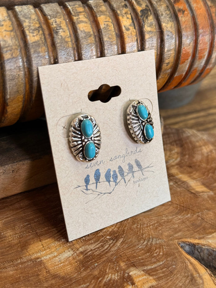 Silver-tone turquoise double concho stud earrings with oval stones, angled view on card