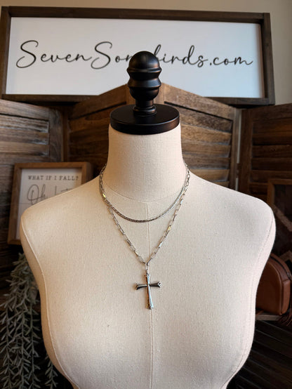 Silver-tone chain necklace with a hanging cross pendant, layered design