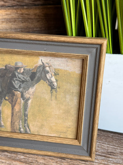 Framed cowboy and horse artwork detail, textured canvas inside gray border