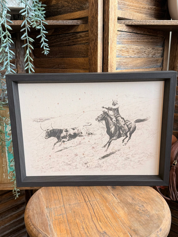 Framed cowboy roping longhorn scene print in dark gray frame