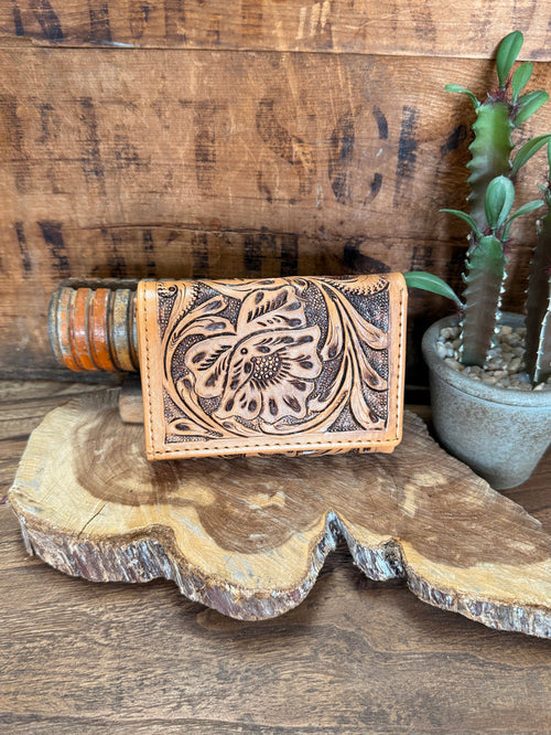 Tan trifold cowhide wallet with embossed floral tooling and snap closure