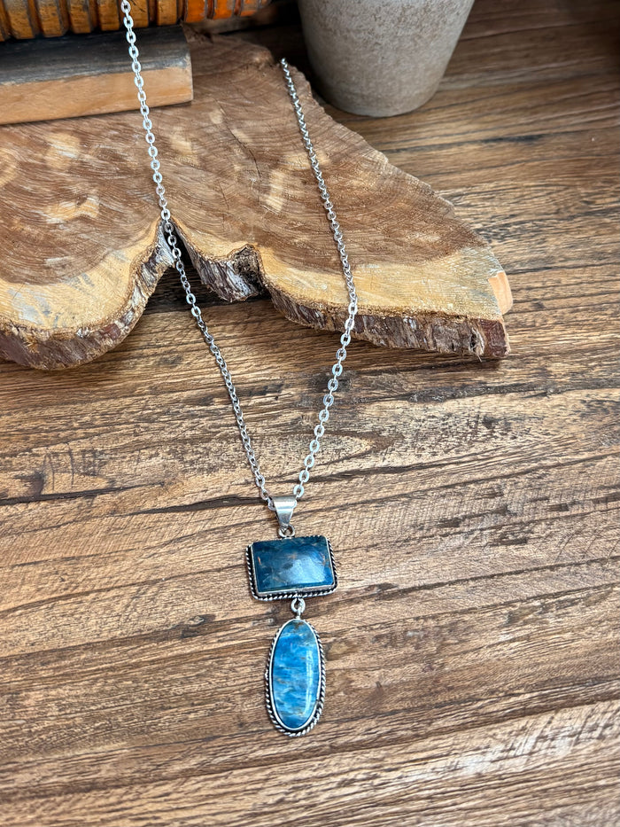 Silver lariat necklace with blue rectangular top pendant and blue oval bottom pendant