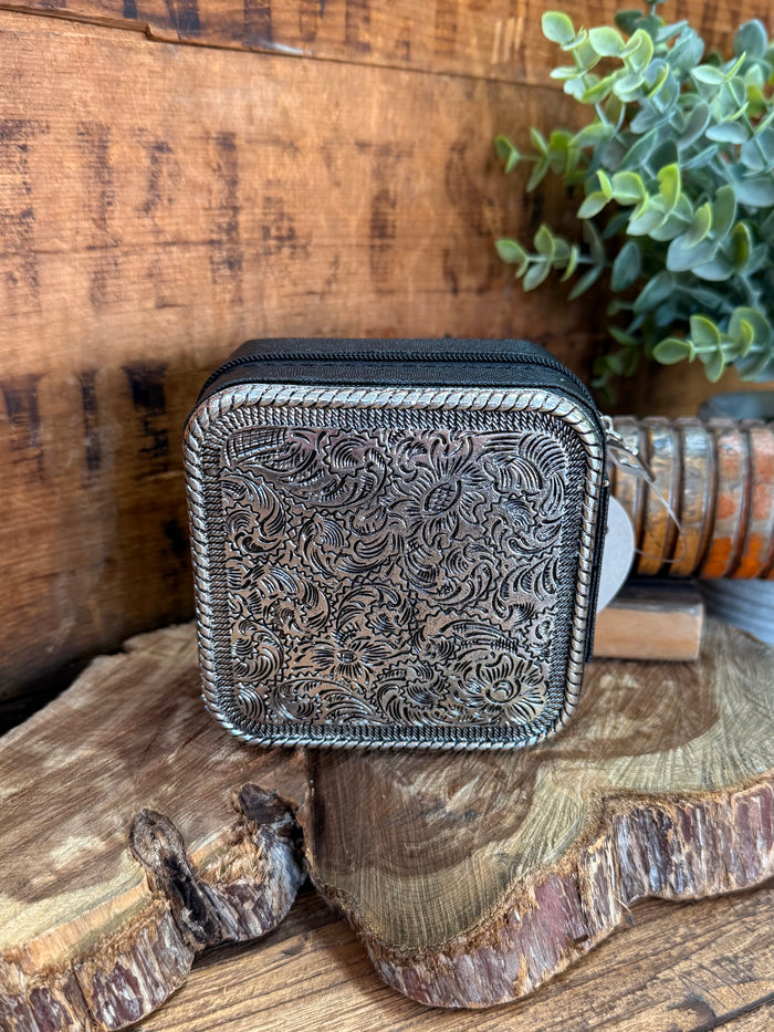 Engraved metal travel jewelry box with dark exterior and silver scroll pattern, front