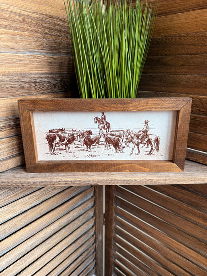 Rectangular wood framed cattle drive print with cowboys herding horses and cattle