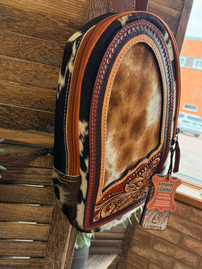 Hair-on cowhide sling bag with tan-brown hide front and genuine leather label