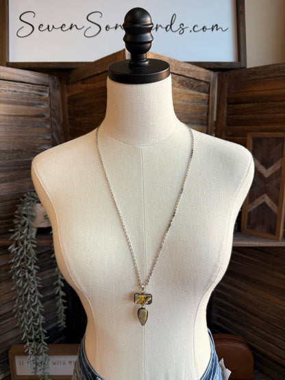 Lariat-style silver necklace on a mannequin with two blue-yellow stone pendants