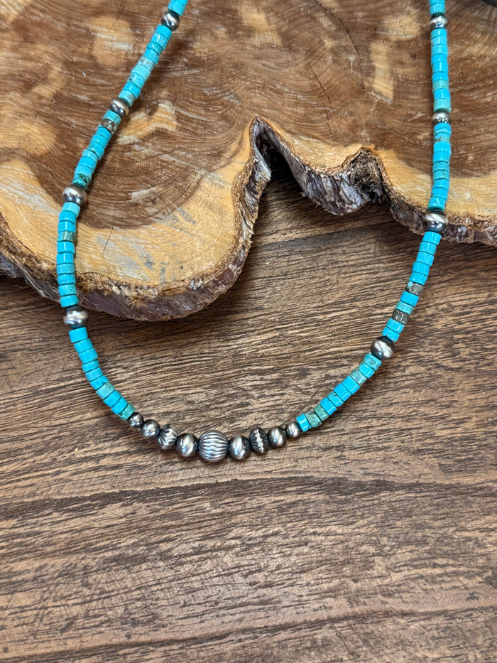 Turquoise heishi bead necklace with silver oval spacer beads along the front