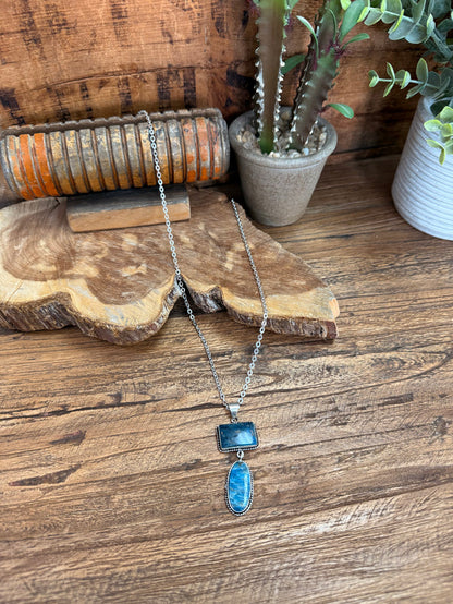 Silver lariat necklace with rectangular and oval blue stone pendants on a chain