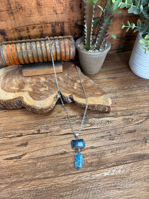 Silver lariat necklace with rectangular and oval blue stone pendants on a chain