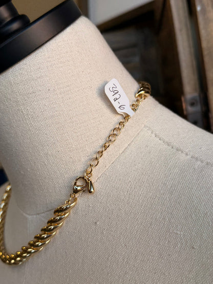 Chunky gold chain necklace clasp detail with tag on mannequin, twisted curb links