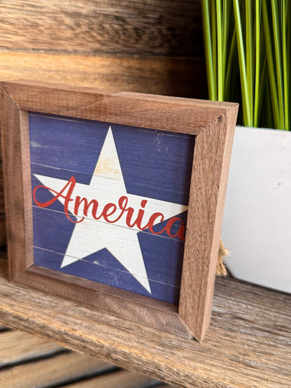 Framed blue star artwork with red America script in rustic wood 4x4 frame (tilted)