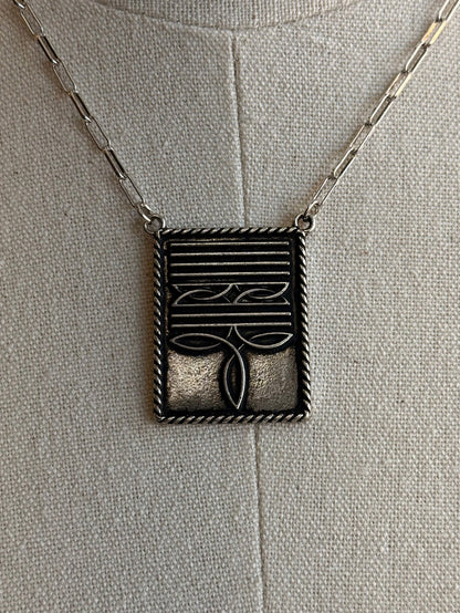 Rectangular boot-stitch pendant with engraved lines, shown on a chain